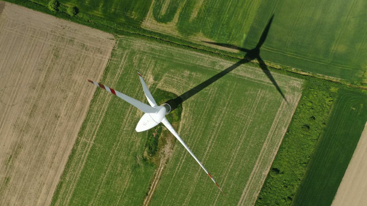 Aerial view of wind turbine with shadow on agricultural field.