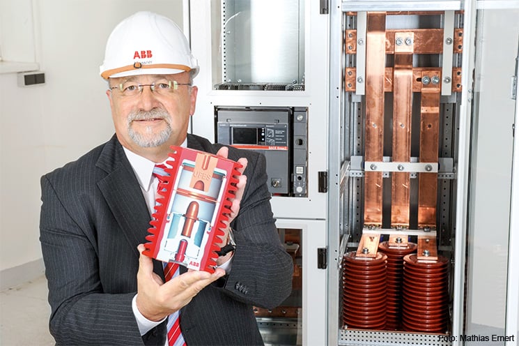 Hans-Dieter Meißner zeigt ein UFES-Primärschaltelement im Querschnitt: Im Ereignisfall treibt ein Mikro-Gasgenerator den beweglichen Kontakt über die Schaltstrecke in den Festkontakt.